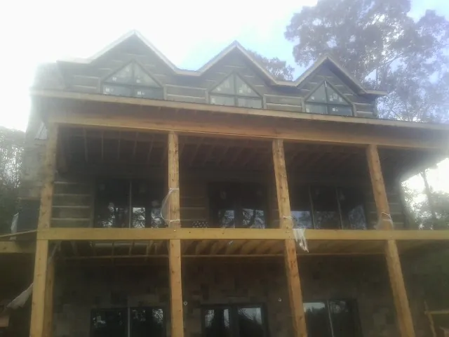 Dormers and porch framing on a large log home under construction — Roof Coating work by our crew in Lindale