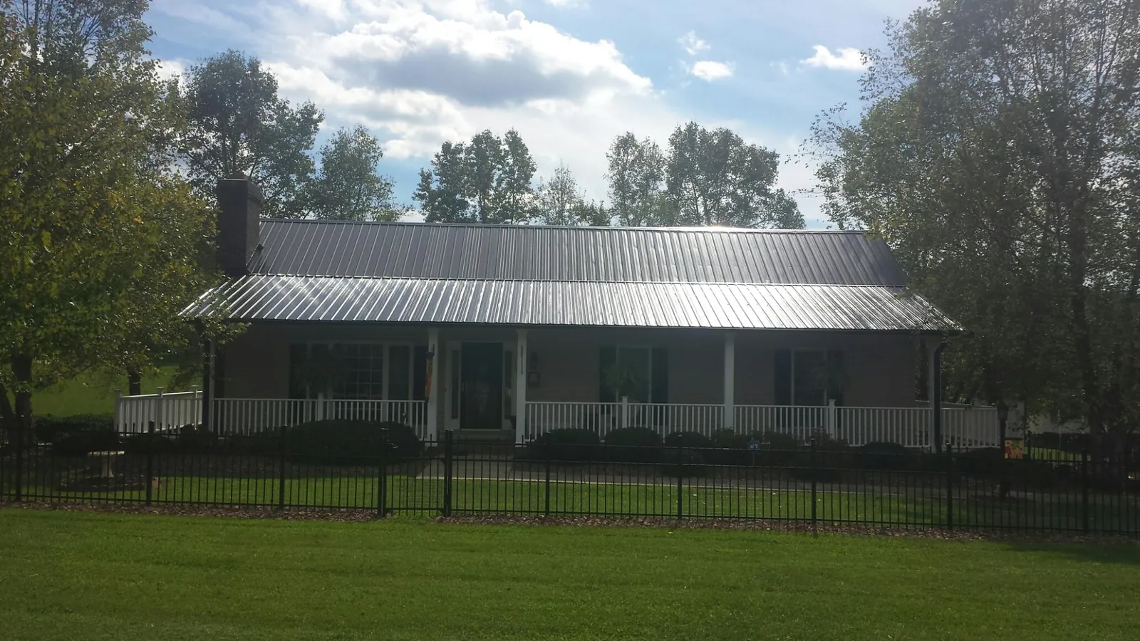 Gray metal roof on a brick ranch with a full width front porch — Gutter Guard Installation work by our crew in Lindale